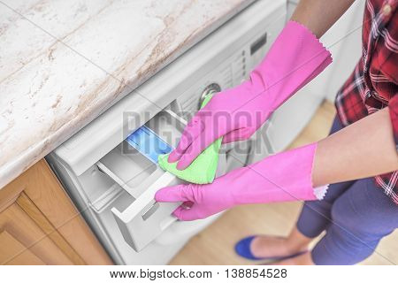 Female hands in gloves washing washing machine. Close-up.