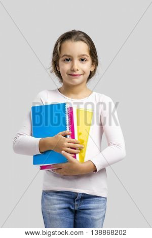 Smiling little student girl holding notebooks