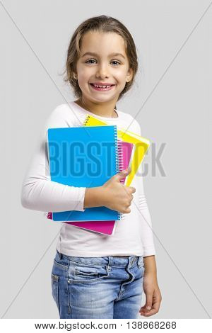 Smiling little student girl holding notebooks
