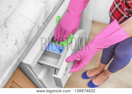 Female hands in gloves washing washing machine. Close-up.