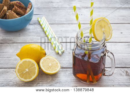 Iced tea with lemon slices and raspberry chip cookies on rustic background. Focus on ice tea