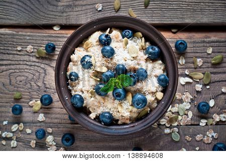 Oatmeal with blueberries coconat and seeds at rustic wooden table. Flat lay.