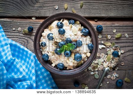 Oatmeal with blueberries coconat and seeds at rustic wooden table. Flat lay.