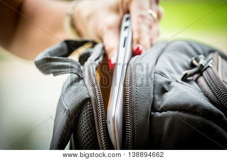 Before a travel - woman packs her computer to a backpack