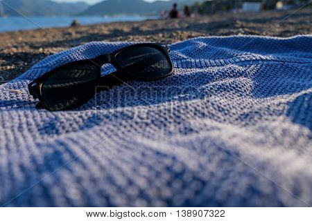 Sunglasses on blue towel on the beach