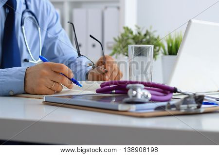 Male doctor using a laptop sitting at his desk .