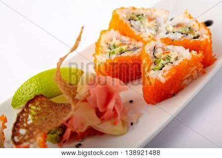 Plate of salmon sushi with lime and ginger on a white background