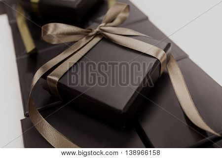Beautiful black jewelry box with a brown bow on the background of other boxes