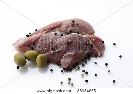 red raw meat piece with vegetables and greens on a white background