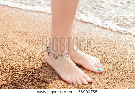 close-up of legs and a piece of jewelry for your feet. Young adult woman feet and toes, wearing anklet ankle bracelet resting in a summer vacation trip.