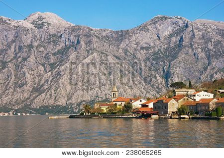 Small Mediterranean Village With Stone Houses With Red-tiles Roofs Against Gray Mountains. Montenegr