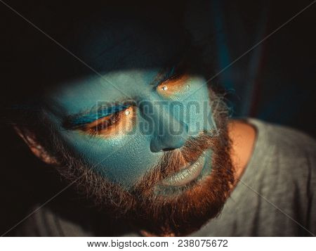 Portrait of a man with a blue make-up on his face. Stage make-up, like an alien, fantasy