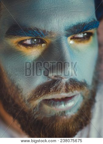 Portrait of a man with a blue make-up on his face. Stage make-up, like an alien, fantasy