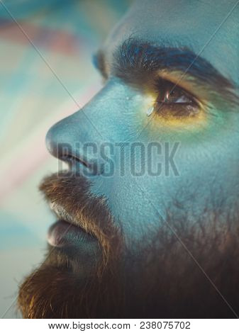 Portrait of a man with a blue make-up on his face. Stage make-up, like an alien, fantasy