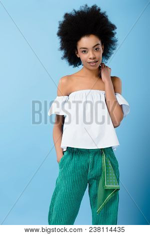 Smiling Young Woman In Stylish Off-the-shoulder Top Looking At Camera Isolated On Blue