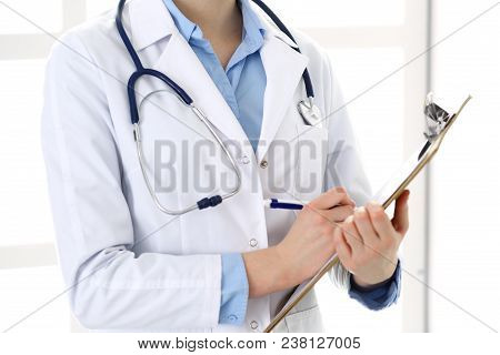 Female Doctor Filling Up Medical Form On Clipboard Closeup.  Physician Finishing Up Examining His Pa