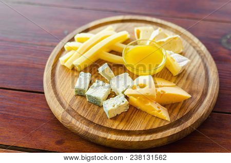 Cheese Plate. Assortment Of Various Types Of Cheese On Wooden Cutting Board.