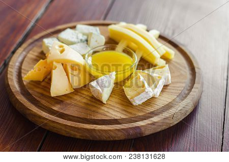 Cheese Plate. Assortment Of Various Types Of Cheese On Wooden Cutting Board.