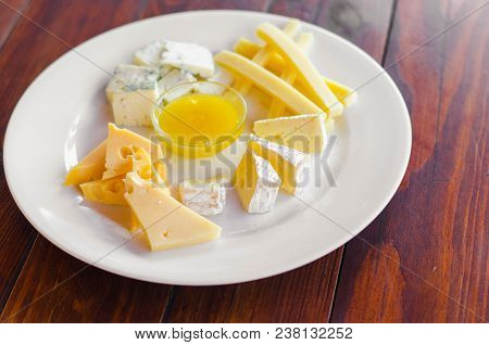 Cheese Plate. Assortment Of Various Types Of Cheese On Wooden Cutting Board.