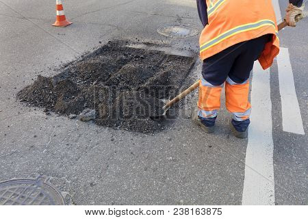 Servant For Road Maintenance Removes The Old Asphalt By Shovel In Road Construction