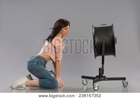 Young Brunette Woman With Raised By The Wind Machine. Studio Shot Over Gray Background