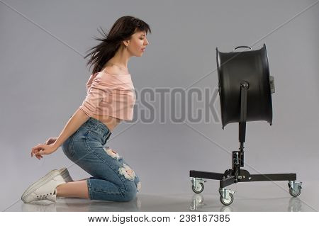 Young Brunette Woman With Raised By The Wind Machine. Studio Shot Over Gray Background
