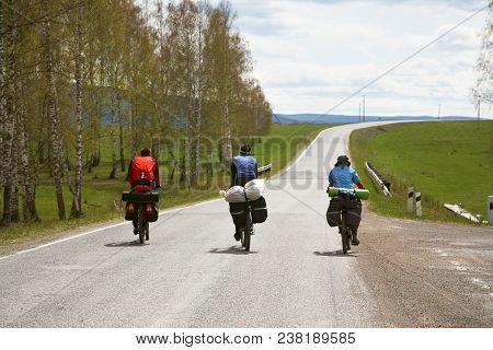 Group Of Tourists In A Hike On Bicycles With Backpacks. Travelers On Bikes. Bicycle Tourism