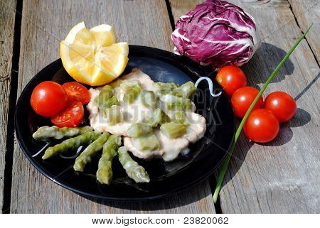 Scaloppina di vitello nel piatto nero con pomodori