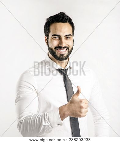 Portrait Of Bearded Eastern Man Dressed In White Shirt And Black Tie Shows Thumb Up Sign On Isolated