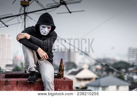 Mystery Man In White Mask With Hoody Jacket, Sitting And Hugs His Knees Up With Broken Empty Bottle.