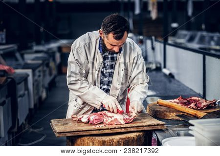 Bearded Butcher Dressed In A Fleece Shirt Cut Fresh Bacon Meat.
