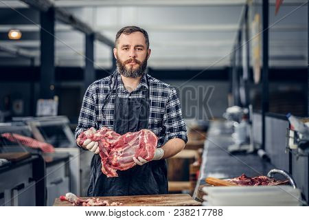 Portrait Of A Bearded Meat Man Dressed In A Fleece Shirt Holds Fresh Cut Meat In A Market.
