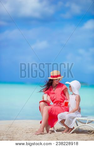 Mother And Little Daughter Relaxing On Beach Chairs At Trpical Vacation
