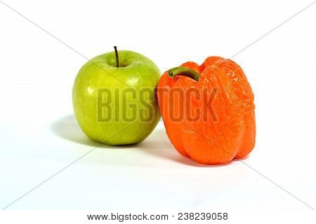 Green Apple Next To Sluggish Orange Bell Pepper On White Background Isolated.