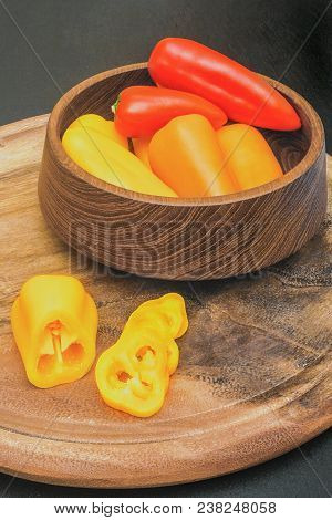 Red, Orange And Yellow Mini Paprika In Wooden Utensils And On A Cutting Board
