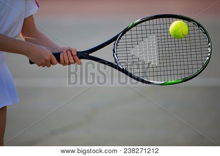 Tennis Racket In The Hands Of The Child Beats The Ball