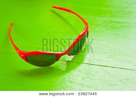 Occhiali da sole rossi sul tavolo verde