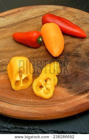 Red, Orange And Yellow Mini Paprika In Wooden Utensils And On A Cutting Board