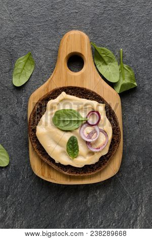 Open faced hummus sandwich canape or crostini on a wooden serving board  on dark stone background closeup. Top view.