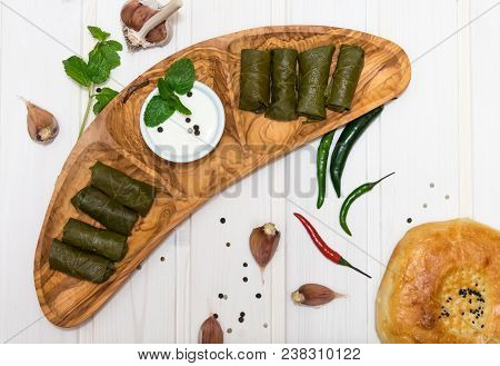 Dolma On Wooden Plate With Hot Peppers, Garlic, Mint And Sour Cream On White Background