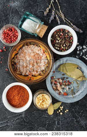 Pink, Gold And White Salt, Black And Red Peppercorns, Bay Leaf, Paprika On A Black Background Top Vi