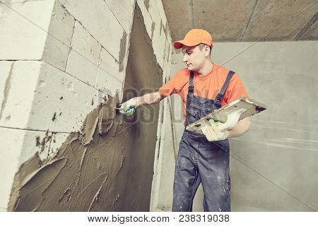 Plasterer applying plaster on block wall. Rennovation