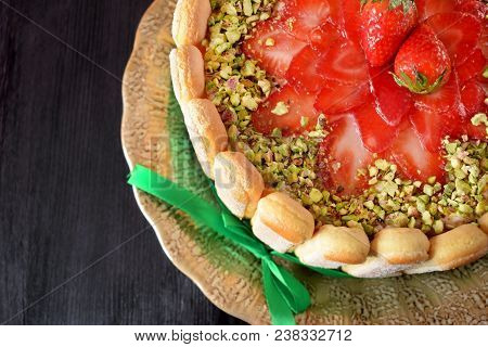 French Charlotte Cake With Savoyardi Biscuits, Strawberries And Pistachio Nuts Decorated With A Gree