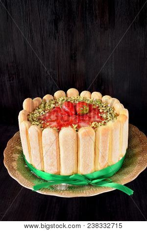 French Charlotte Cake With Savoyardi Biscuits, Strawberries And Pistachio Nuts Decorated With A Gree