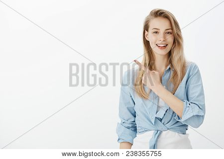 Confident Feminine Female Shop Assitant In Stylish Clothes, Raising Index Finger And Pointing At Upp