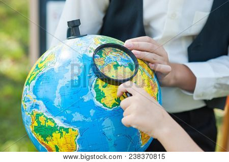 School Boy Looking At Russion Globe Sitting At A Desk On The Background Autumn Park