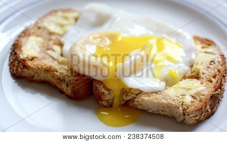 Runny Poached Egg On Brown Buttered Toast