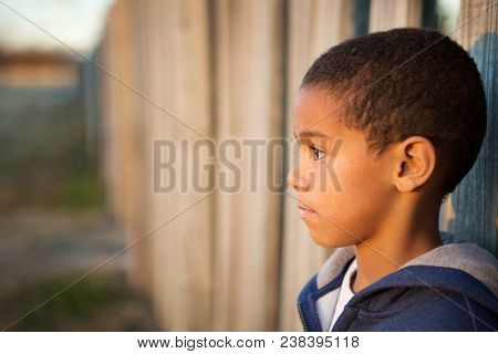 Portrait Of A Sad Lonely Little Boy Outside On A Brick Wall.