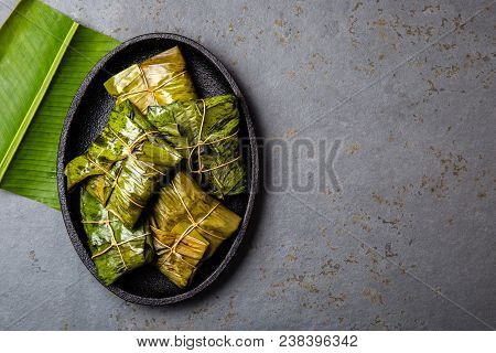 Colombian, Central American Food. Tamales Wrapped In Banana Palm Tree Leaves On Black Plate, Gray St