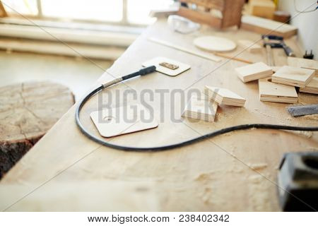 Pyrographic equipment and pieces of wooden planks on workbench of carpentry master